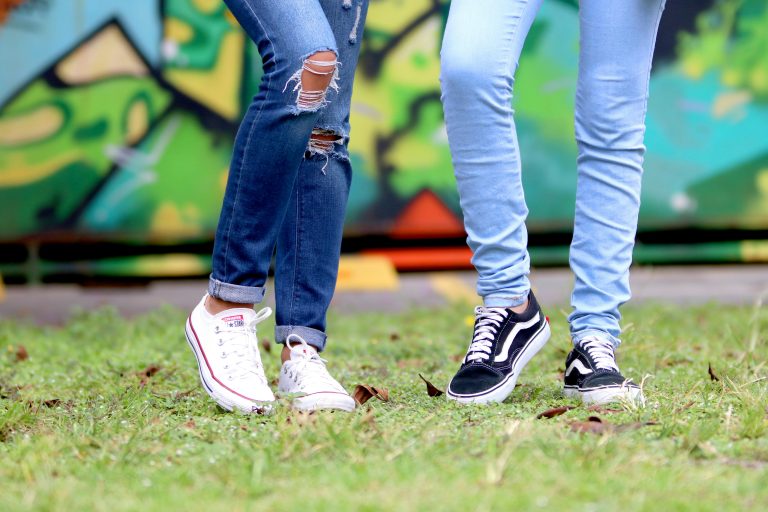Two young adults wearing trendy jeans and sneakers enjoying a lively outdoor setting.